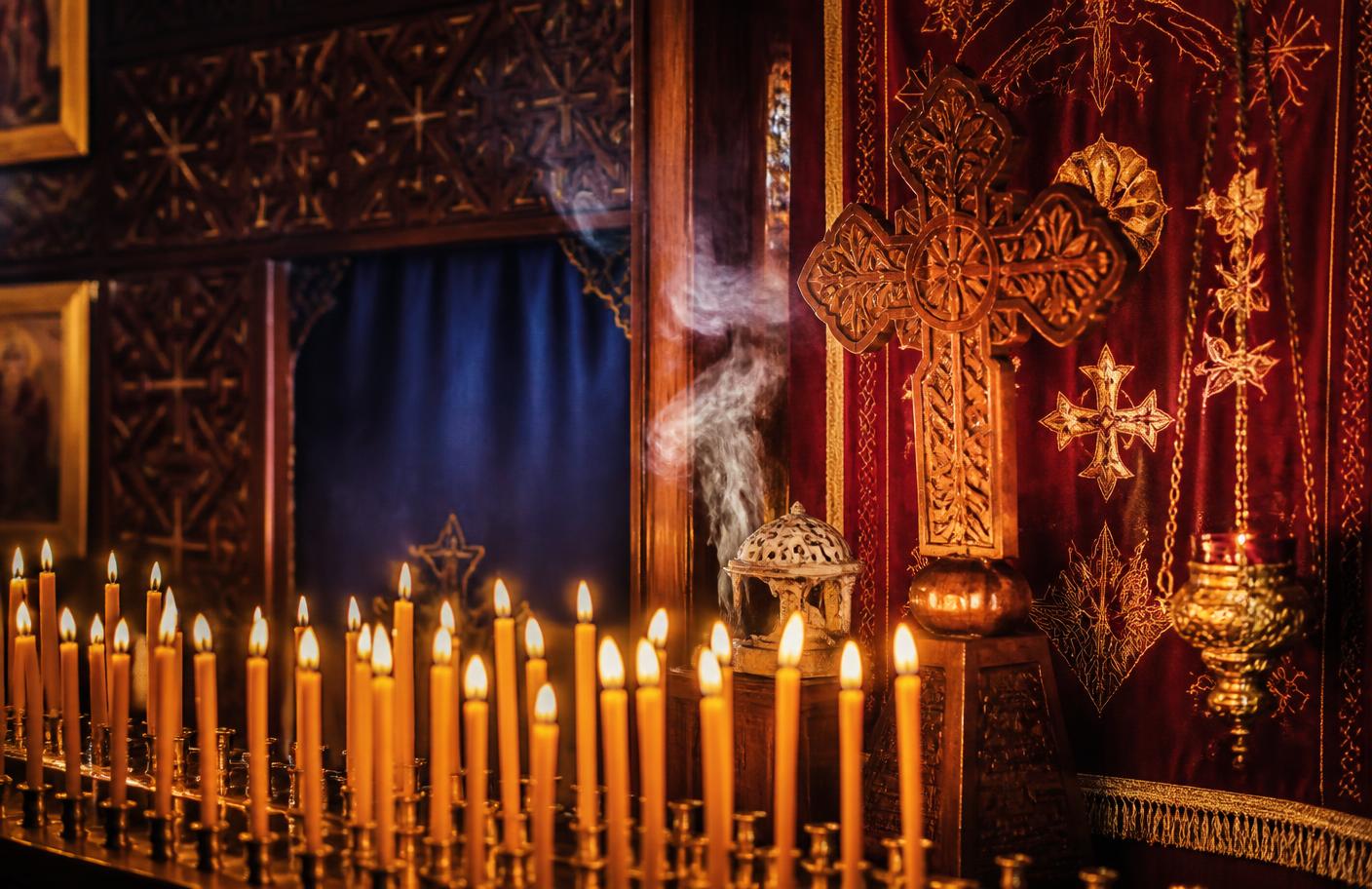 Rangée de cierges et croix copte dans une lumière de prière